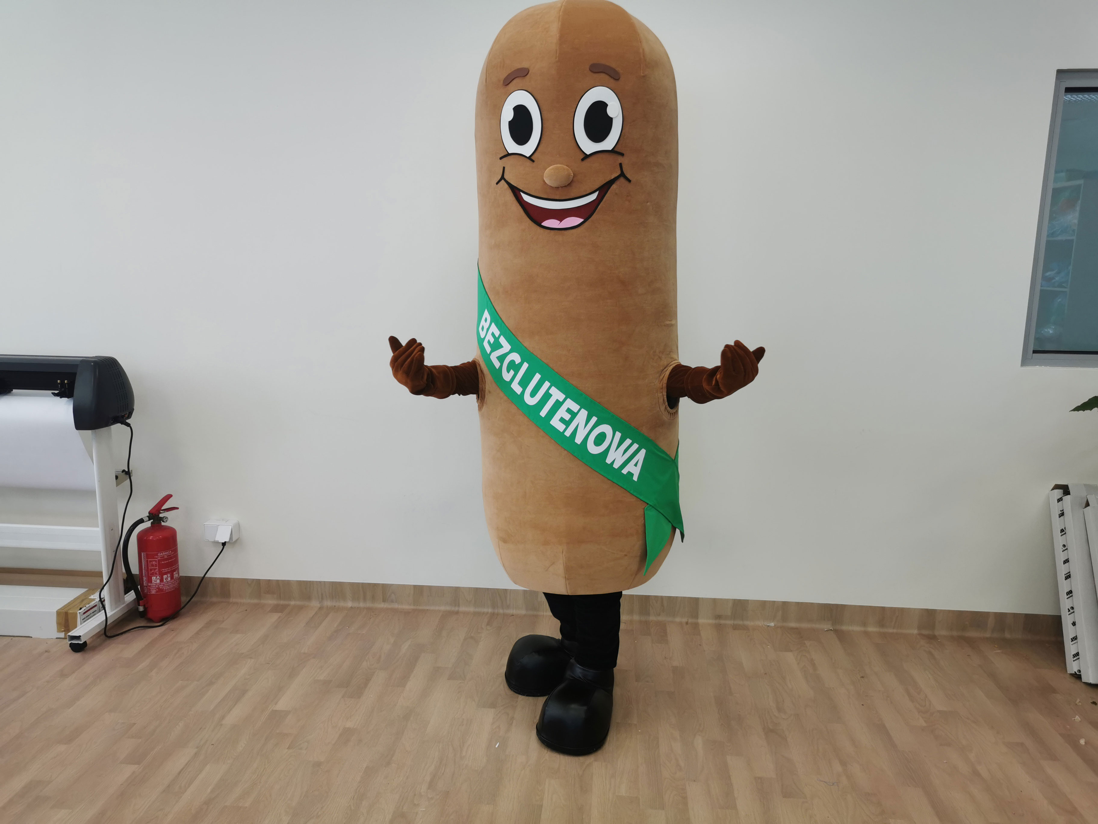 Na fotografii widnieje kostium reklamowy w postaci parówki pozujący do zdjęcia w siedzibie firmy Elabika